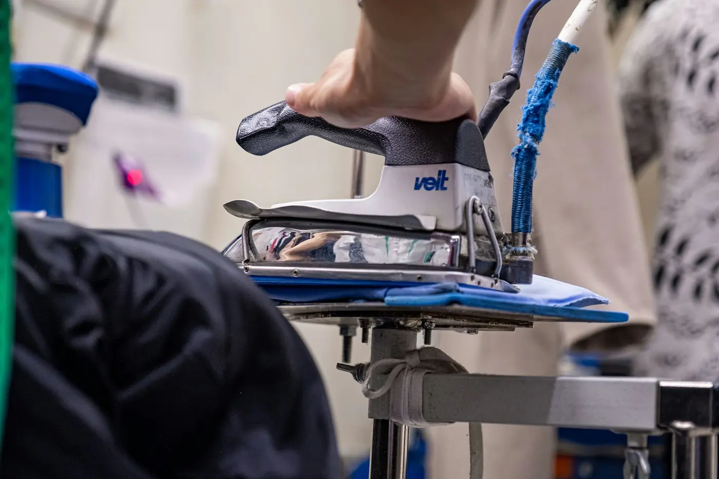 A professional steam press finishing a garment
